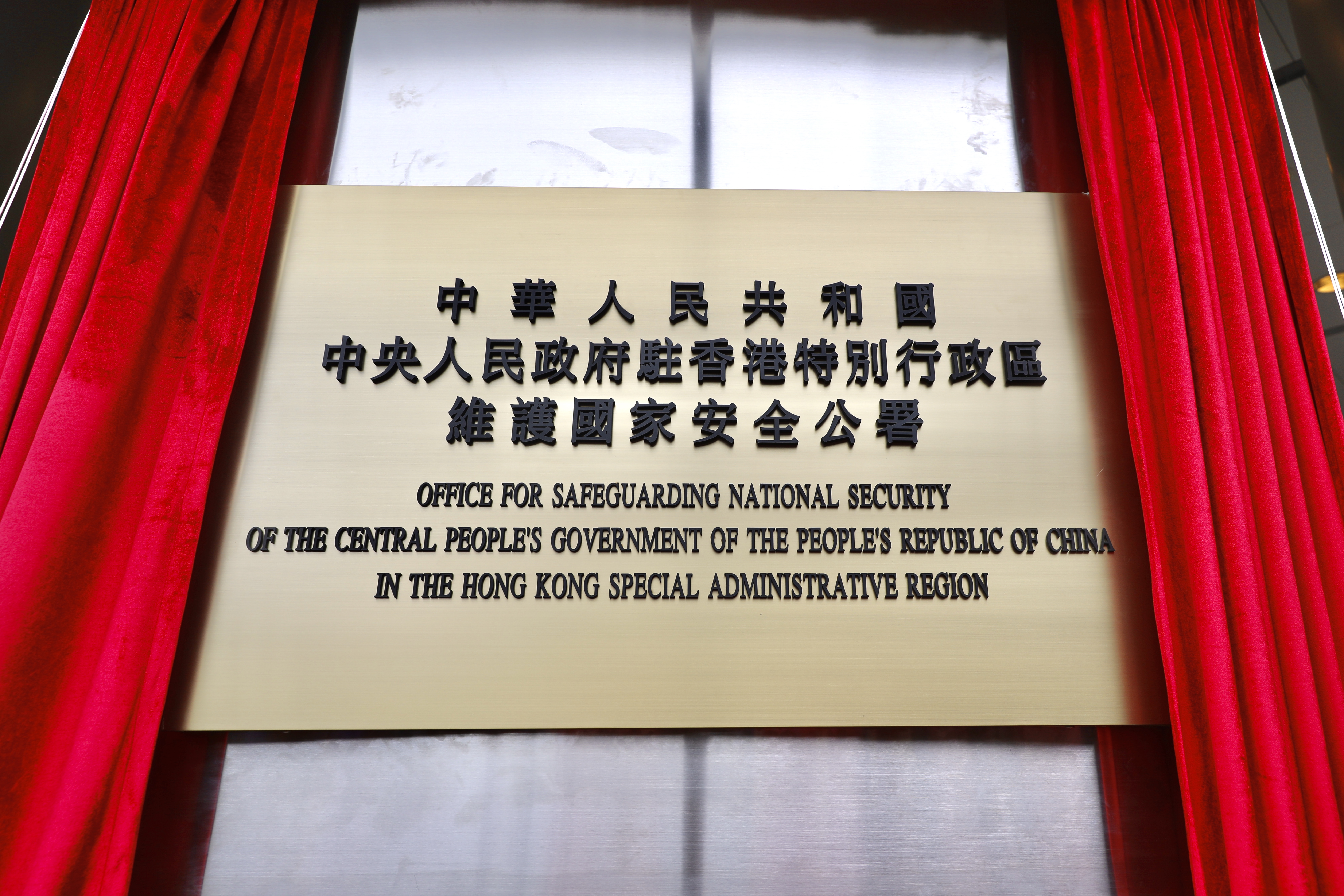 每個人都充滿期待又興奮地，緩緩拉開蓋在國安公署牌子上的紅色幕布。（點新聞記者李斯哲攝）