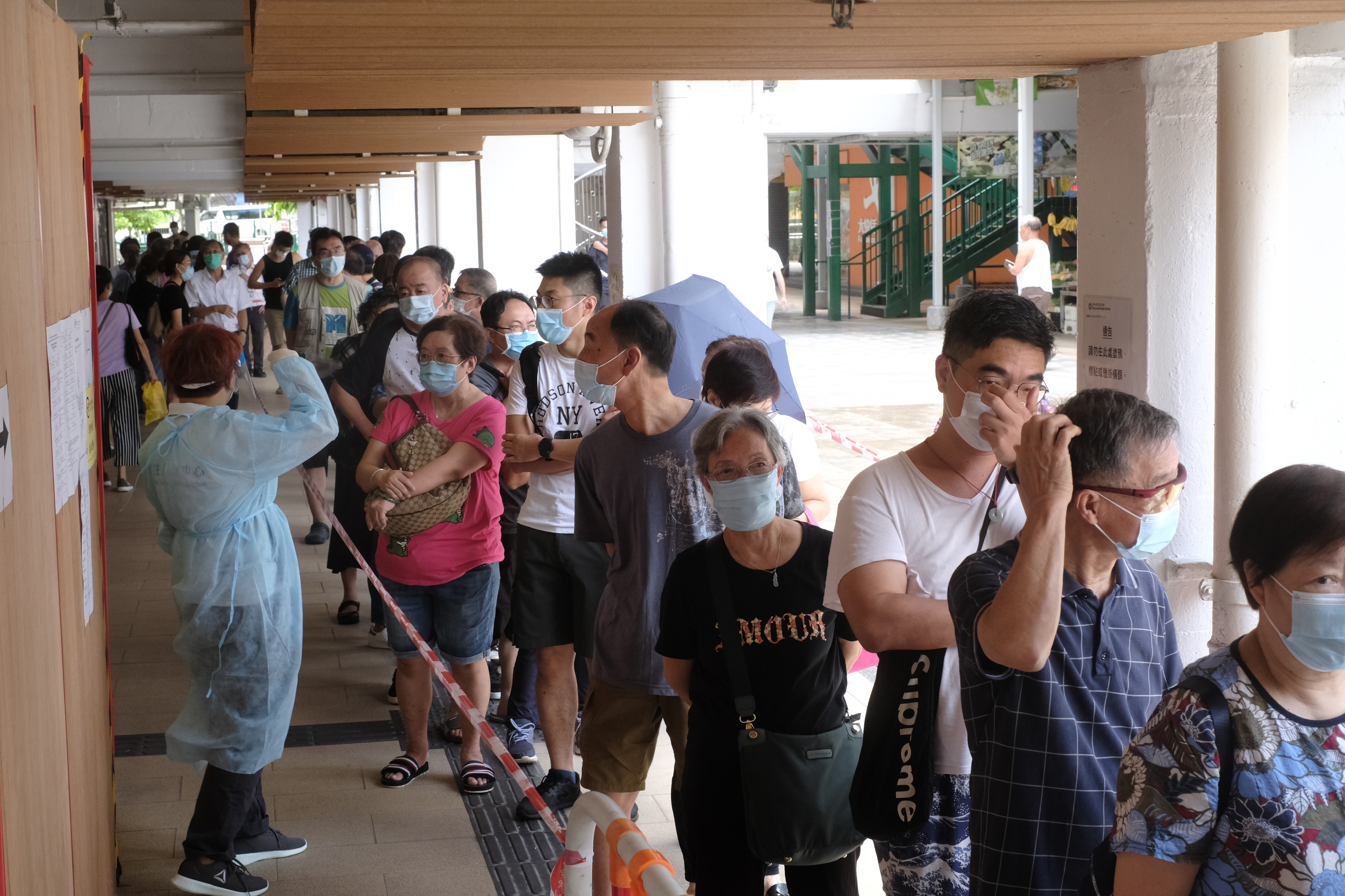 7月6日早上，爆發社區感染的坪石邨玉石樓，居民排隊領取深喉樣本檢測樽和醫用口罩等。（點新聞資料圖片）
